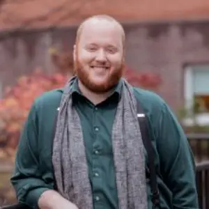 Matt Banks leaning on railing wearing green shirt and gray scarf