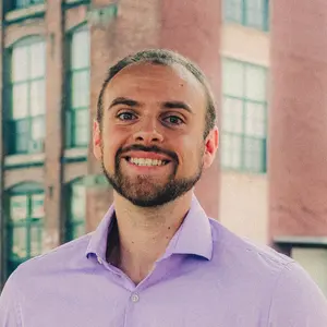 Headshot of Avery Heinz, wearing a purple dress shirt