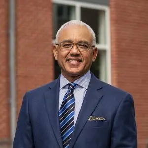 Headshot of President Chrite wearing a dark blue suit and tie with a light blue shirt.