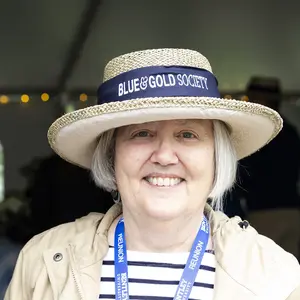 Photo of Edie Blackney smiling and wearing a Blue and Gold Society straw hat