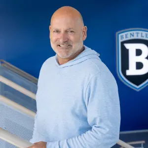 Greg Quercia in the Bentley Arena with the Bentley Athletics logo over his shoulder