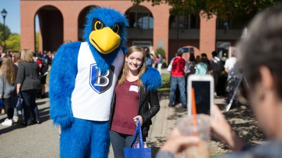 student takes a picture with Flex the Falcon
