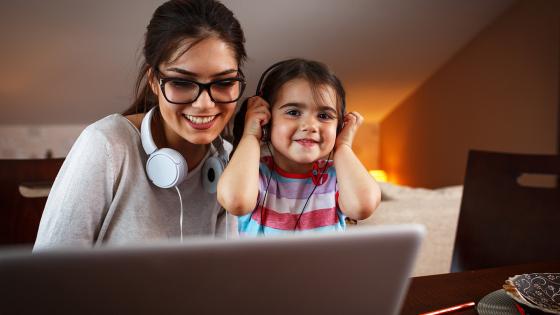 Woman at computer screen learning next to her young daughter