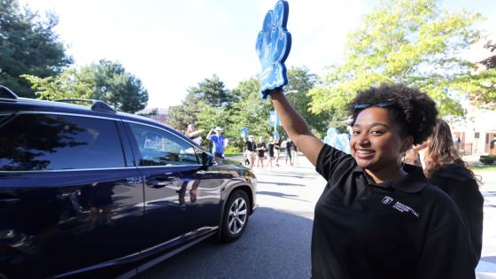 Bentley resident assistant waves to car with incoming student