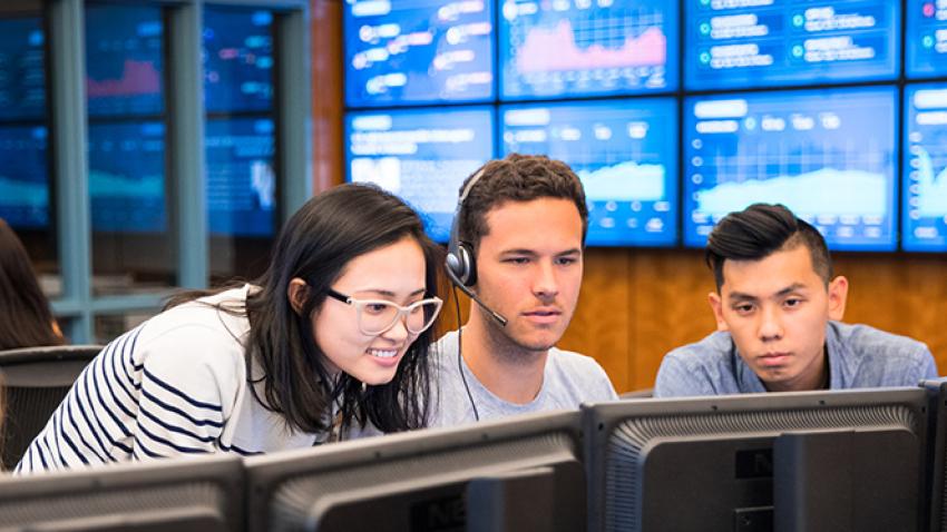 Students working on a computer in the trading room