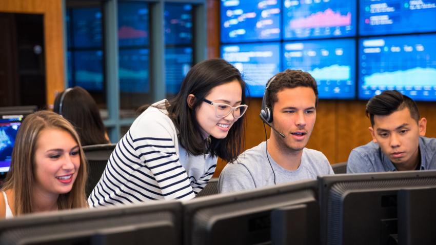 four students in the financial trading room at Bentley