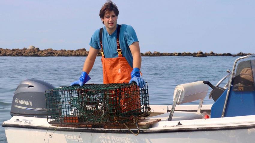 Scott Sawyer '24 on boat holding lobster trap
