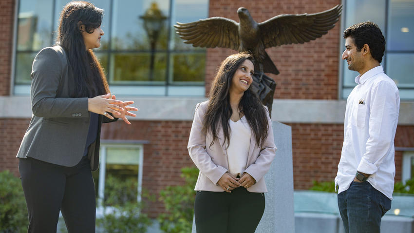 Three international students chatting in front of bentley university library