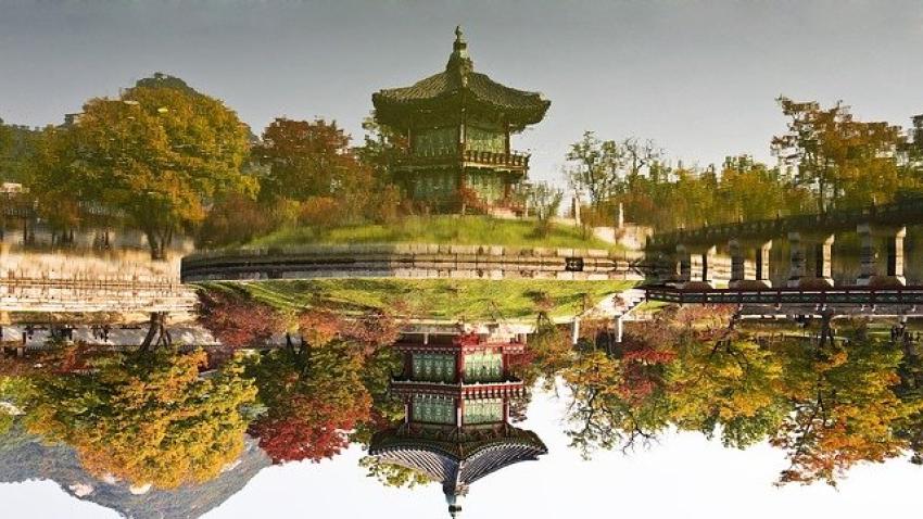 A reflective pond next to a Korean building.