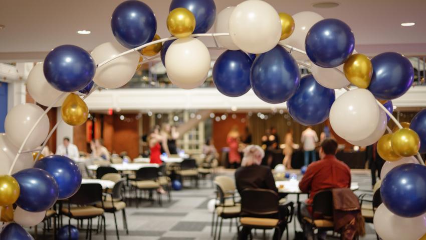 Arch of balloons as attendees enjoy food in the background