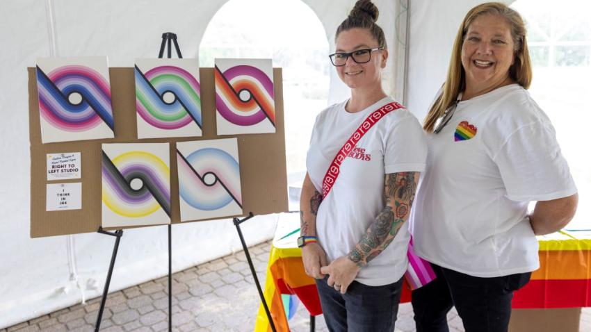 An artist and her mother pose next to colorful artwork 