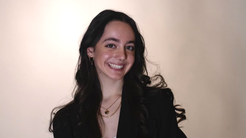 Yasmin in a black blazer and white top smiling at the camera