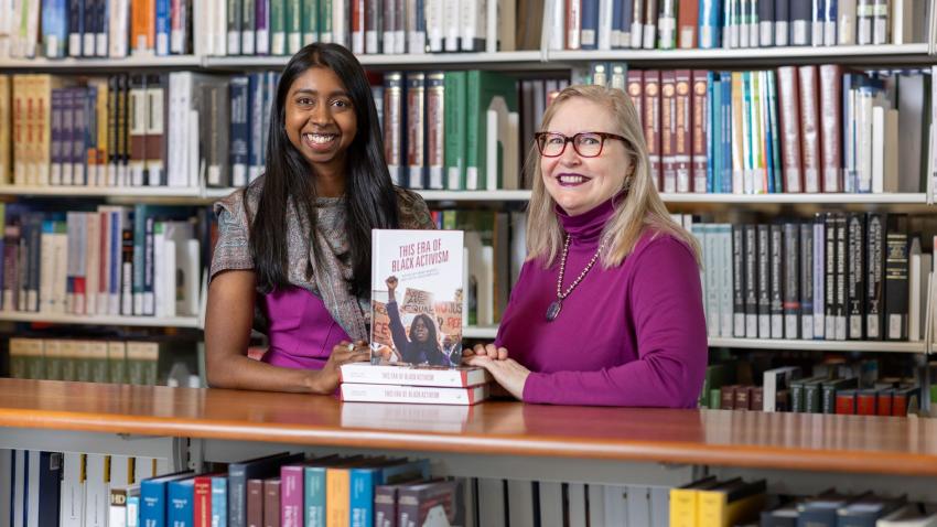 Two women who are authors and editors sit at a table with their book