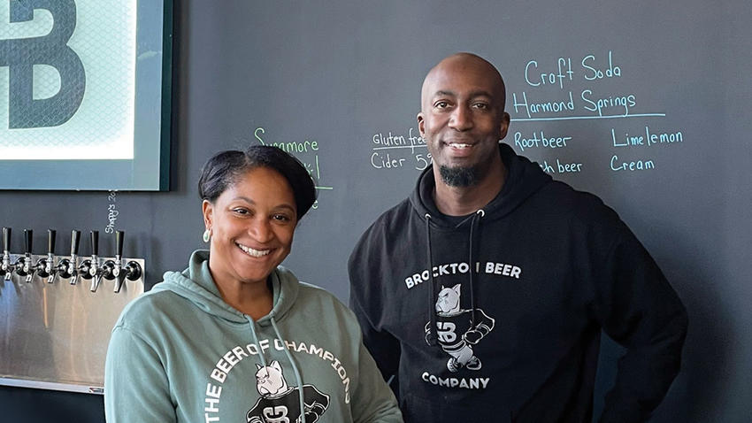 the owners of Brockton Beer Company smile from behind the bar counter