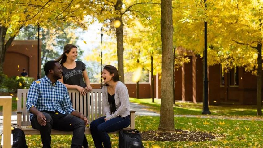  Bentley students on a bench in the fall.