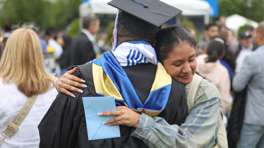 A parent hugs their graduate at commencement 