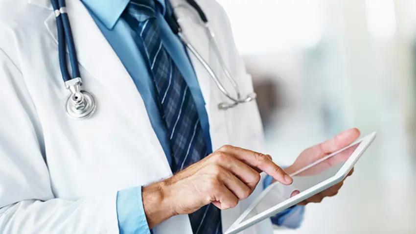Doctor wearing a stethoscope and using a tablet.