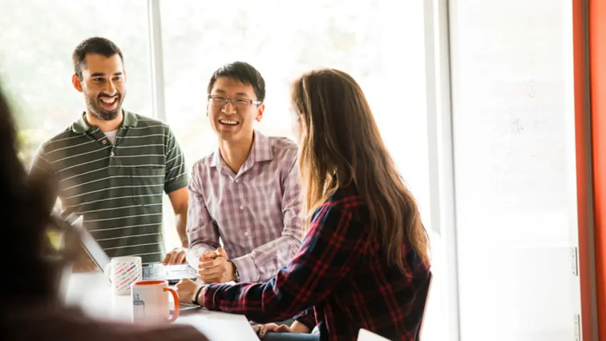 Three graduate students in a conference room smiling