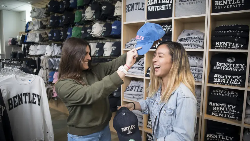 two students try on bentley apparel in bookstore 