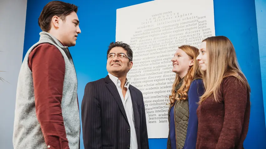 professor christian rubio speaks talks with three students
