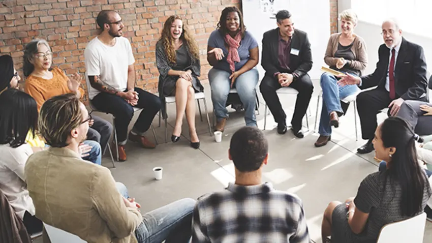 Diverse, multigenerational team having a group discussion sitting in chairs in a circle