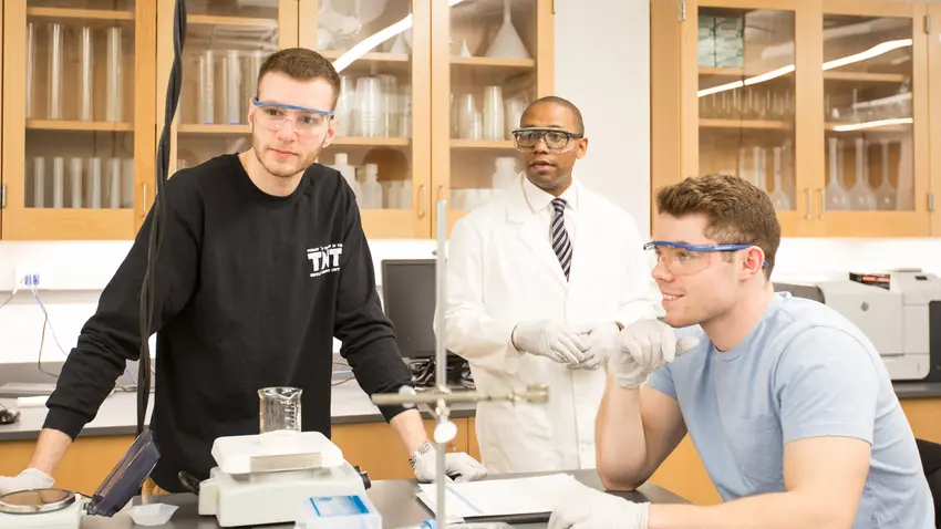 Professor conducting scientific lab experiments with two students.