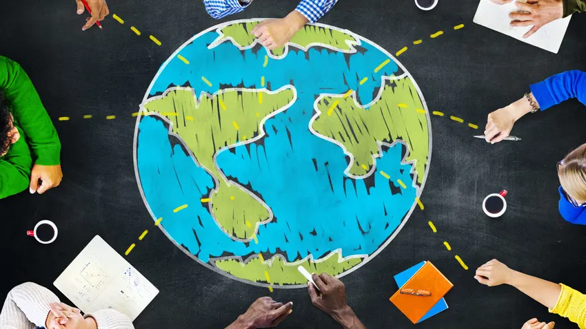 People surround a conference table decorated with large chalk drawing of globe