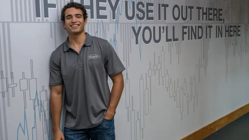 Bentley student Gabriel San Miguel leaning against wall and smiling