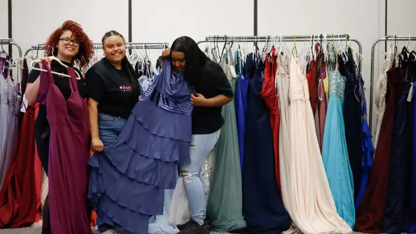 Three Bentley students arranging prom dresses