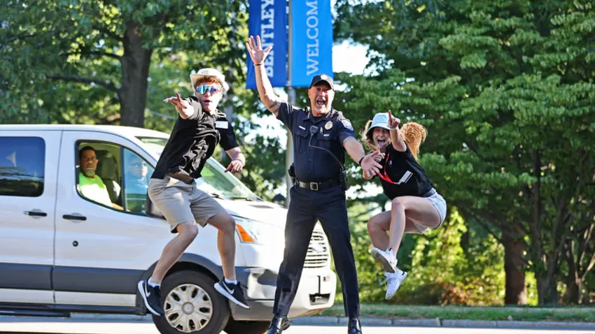 Bentley orientation leaders and University Police officer jump in air