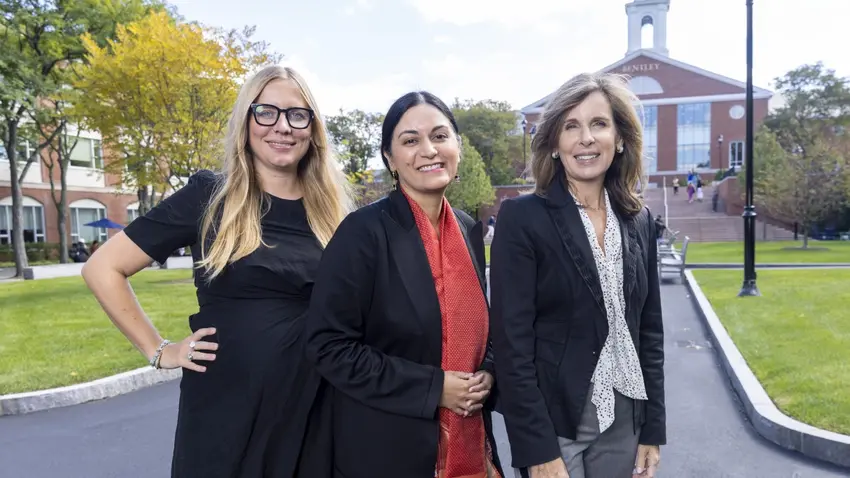 2022 Outstanding Scholarly Contribution Award recipients — from left to right, Marieke Mohlmann, Angma Jhala, and Cynthia Clark — pose together on the Bentley campus, with the library and bell tower in the distance.