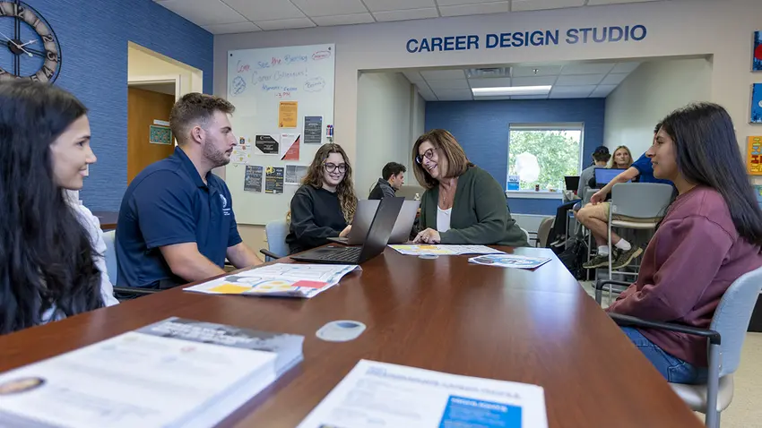 Kristine sitting at a table talking with first-gen students