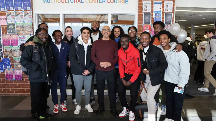 Bentley President LaBrent Chrite stands with a group of students in front of Multicultural Center Lounge sign
