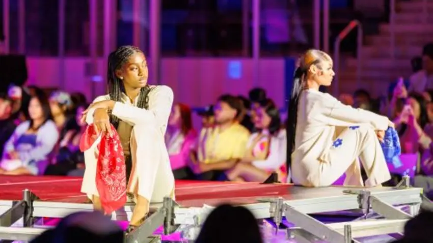 Two models in a sitting pose on runway