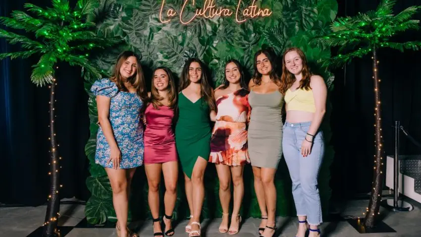 People standing in front of green floral wall