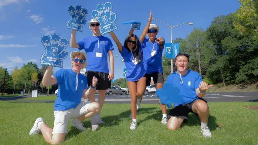 Five Bentley orientation leaders in blue tshirt and foam Bentley hand