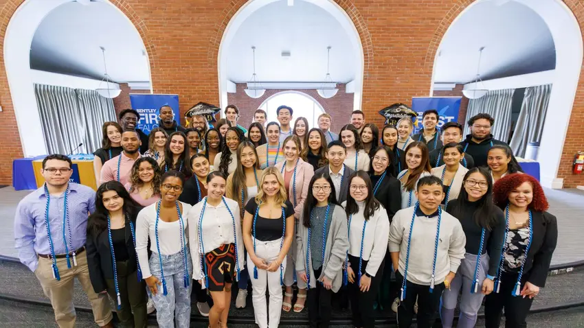 A large group of graduating seniors and first-generation Bentley students pose for a photo after the inaugural First Falcons cording ceremony.