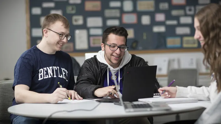 three students work together around a table
