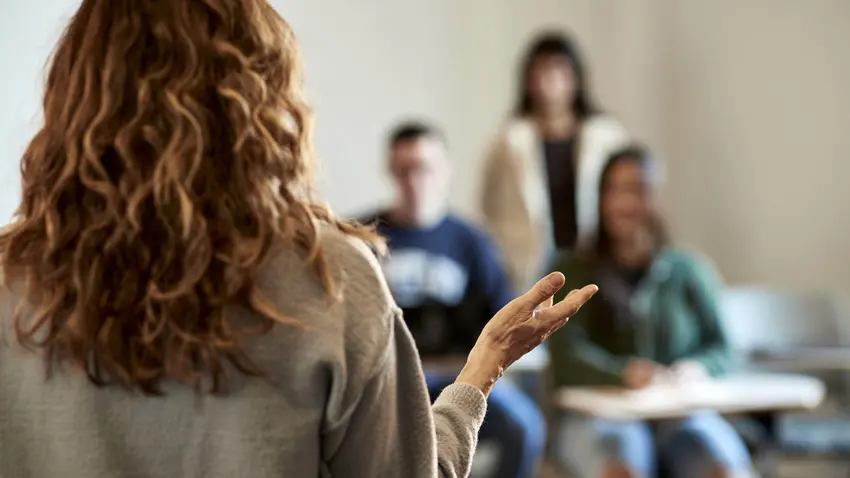 students in classroom looking at teacher presenting