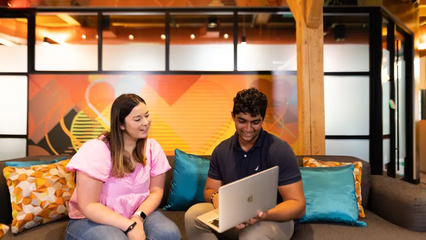 two students look at laptop together