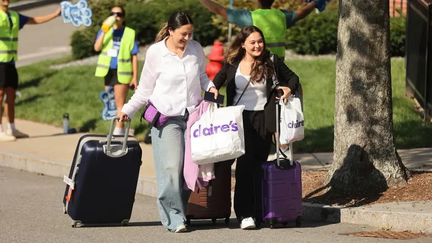 Bentley students moving to campus with rolling suitcases and bags