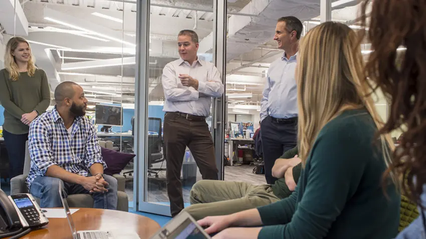 group of people standing around talking in office setting