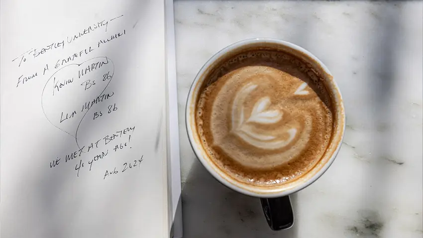 the book All is Well open next to a cup of coffee