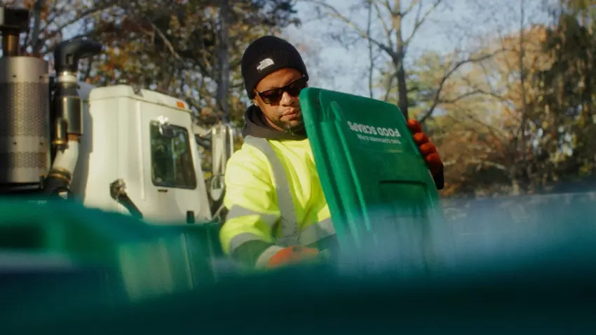 Person in hi vis vest opening recycling container