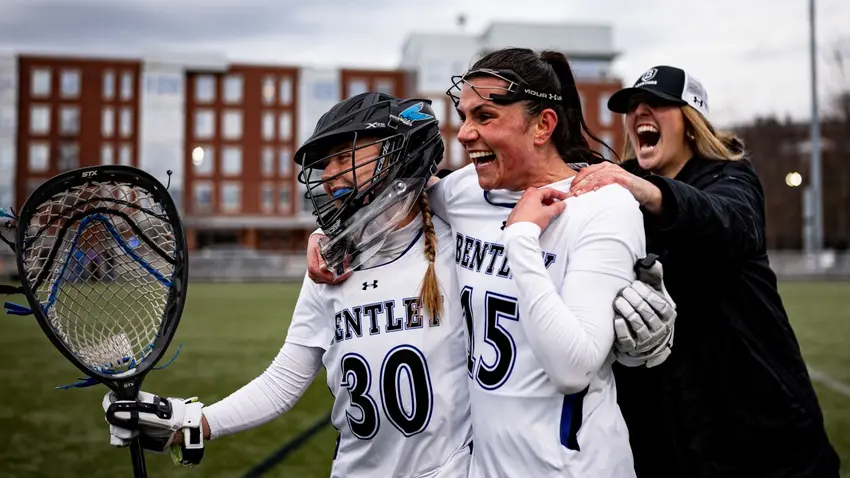 Bentley Women's Lacrosse player Amber Kiricoples celebrates with a teammate and coach during a game