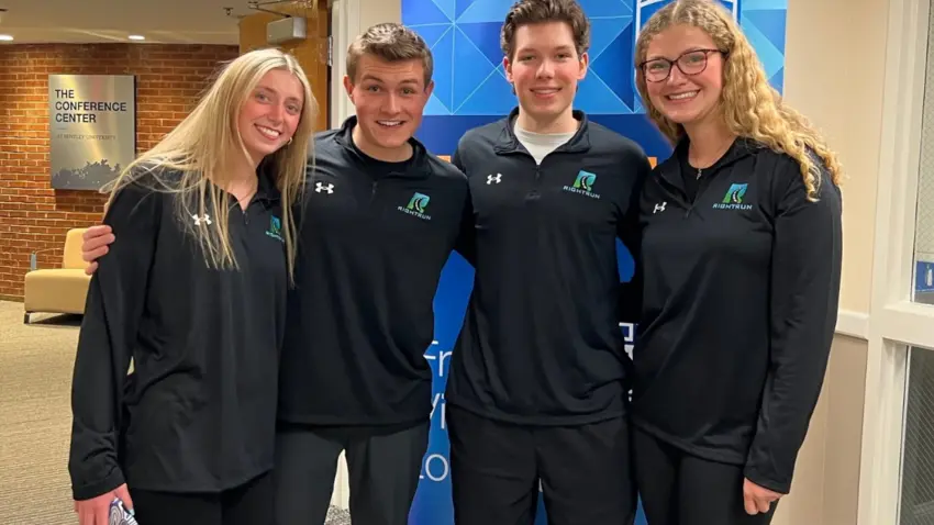 Four Bentley students pose with their arms around each other's shoulders.