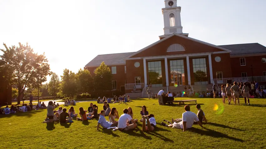 Students gathered on campus lawn during orientation with a clocktower building in the background