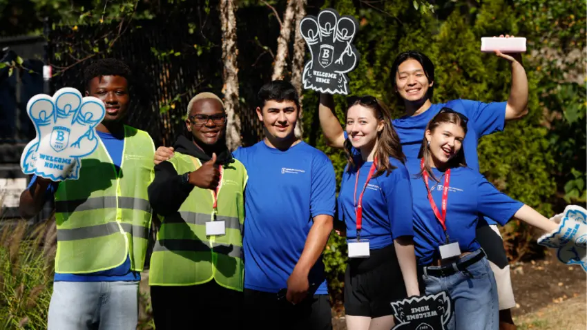 Bentley volunteers pose with thumbs up, foam hands and smiles during Class of 2029 move-in day