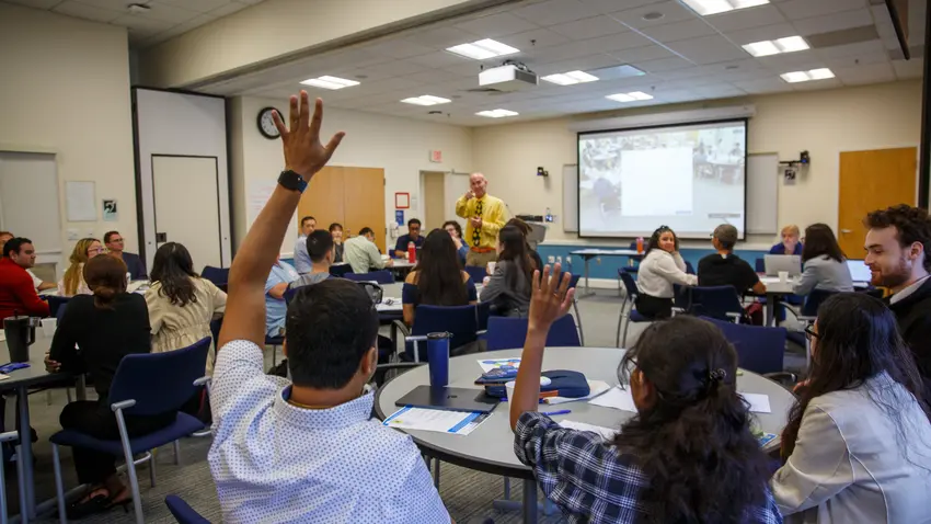 Students with raised hands being called on.