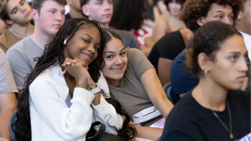 Students from Bentley's Class of 2029, two leaning into each other, during convocation ceremony